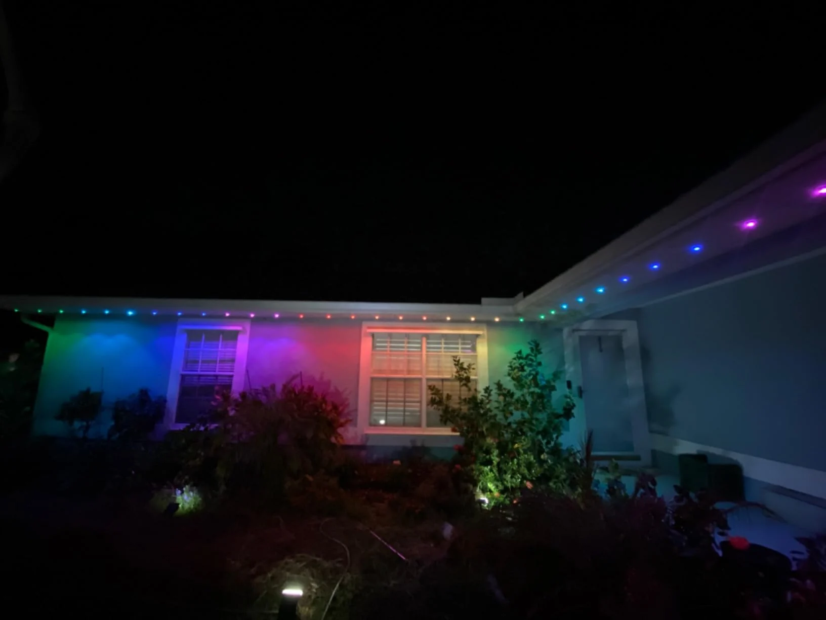 RGBW permanent pixel lights installed along a residential roofline with multicolor illumination