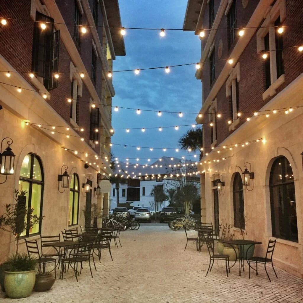 Warm white commercial string lights suspended across a pedestrian courtyard