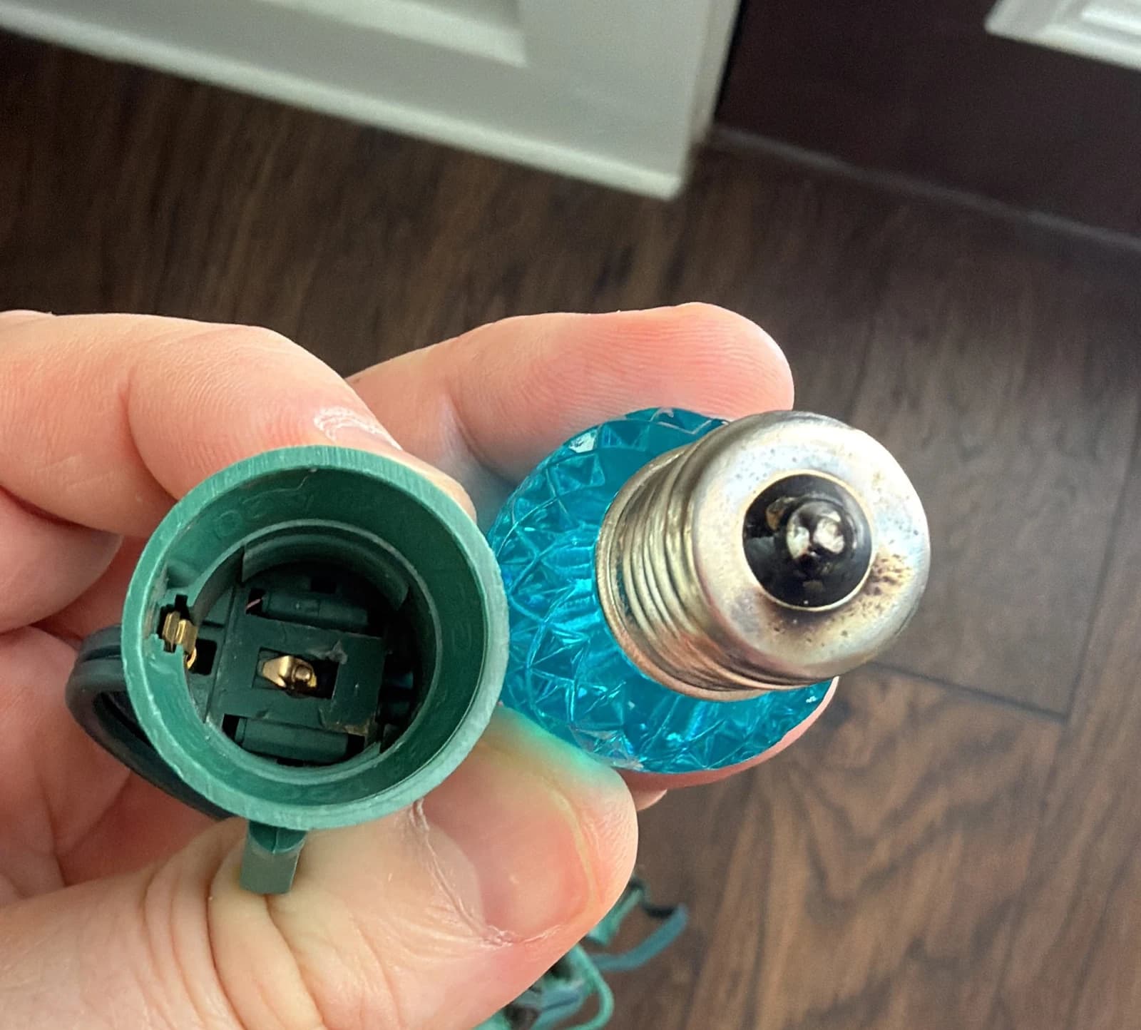 C9 LED bulb with blackened center contact beside an opened green C9 socket