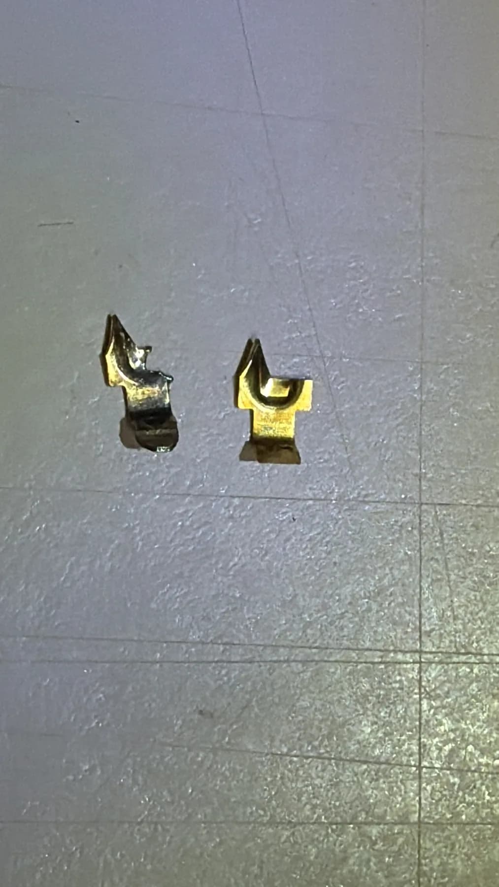 Two removed brass C9 socket contacts showing different shape and heat discoloration